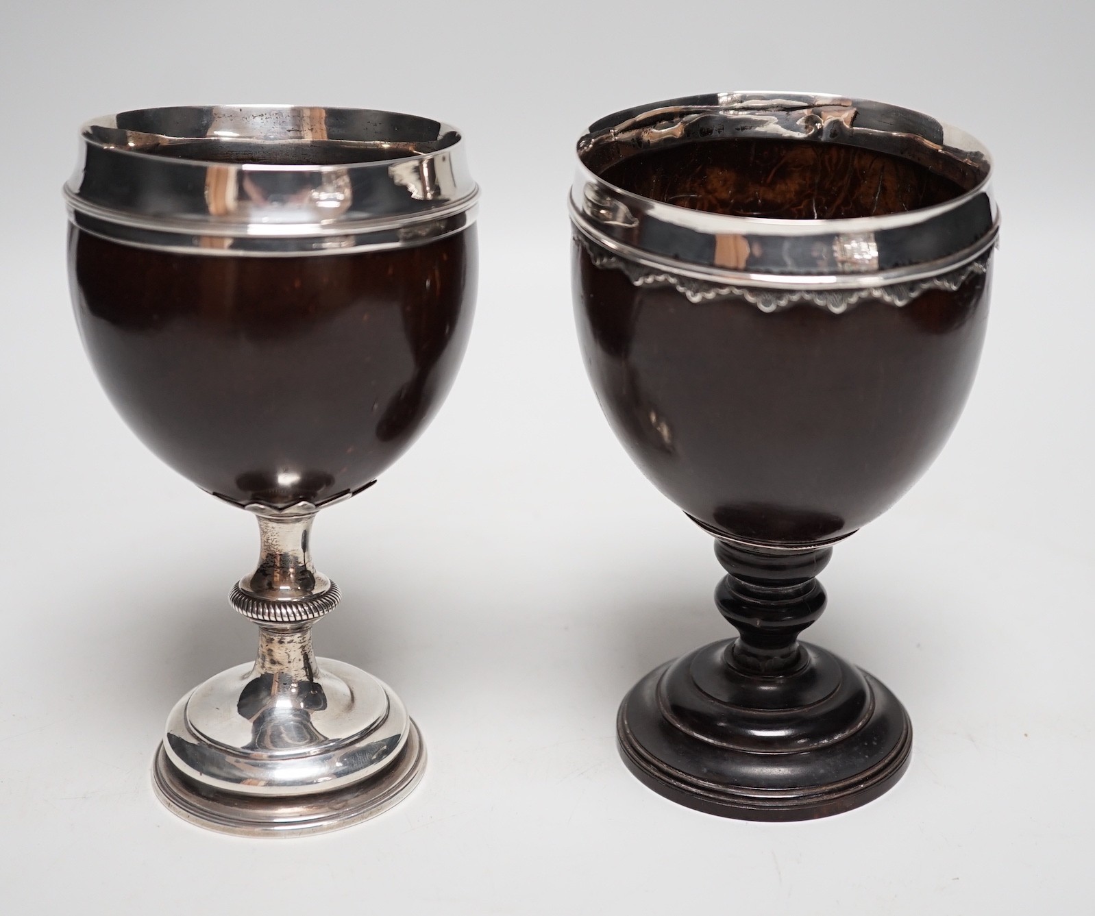 Two late 18th century white metal mounted pedestal coconut cups, one hallmarked silver for John Robbins?, London, 1764, 14.4cm, the other with white metal mounted top rim, on turned wooden base.